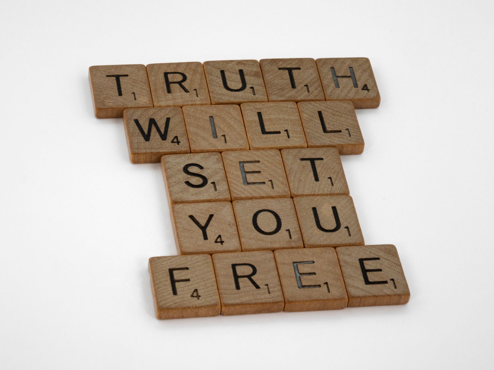 Wooden letter tiles spell out 'TRUTH WILL SET YOU FREE' on a white background.