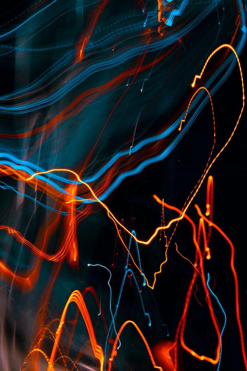 An abstract image featuring swirling lines of blue, orange, and red light against a dark background, creating a dynamic and energetic visual effect.